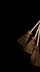 Mini witch brooms on black background, occult props, mystical composition, esoteric tools for magic and rituals