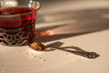 A spoonful of brown sugar with a teacup in the background during tea preparation.