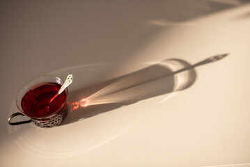 hot teacup with spoon and long shadows