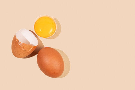 An artistic composition of brown eggs on a yellow background with one cracked egg