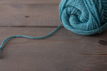 Blue ball of wool on a wooden base with wool thread