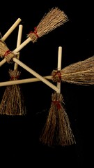 Mini witch brooms on black background, occult props, mystical composition, esoteric tools for magic and rituals