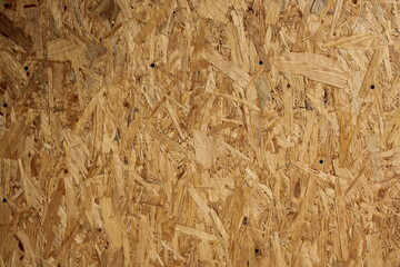 Texture of oriented strand board used in construction taken in a workshop during daytime