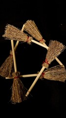 Mini witch brooms on black background, occult props, mystical composition, esoteric tools for magic and rituals