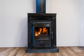 Close up of Fireplace inside house modern living room. Wood burner stove with burning flame behind a glass door