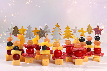 Assorted canapes with tomatoes, mozzarella cheese, salami, pineapple, olives and grapes on a marble...