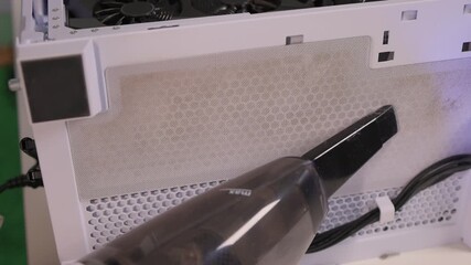 Professional cleaning of graphics card and cooling system essentials, Technician uses handheld vacuum to clean dust from computer fans and heatsinks with detailed precision
