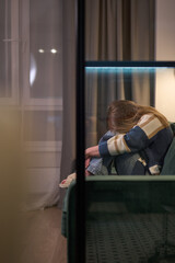 Female curled up on sofa in dimly lit room
