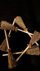 Mini witch brooms on black background, occult props, mystical composition, esoteric tools for magic and rituals