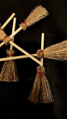 Mini witch brooms on black background, occult props, mystical composition, esoteric tools for magic and rituals