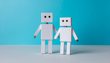 Photo of two simple paper robots, showcasing a playful handmade design. Great for DIY themes, creative projects, crafts, and charming minimal visuals.