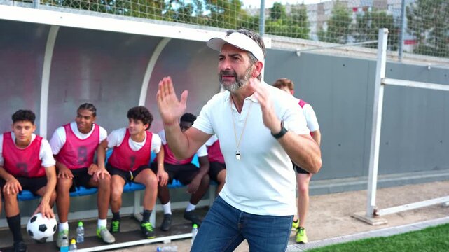 Enthusiastic football team with their coach celebrating a victory. The players jump up from the bench, cheering and hugging in slow motion