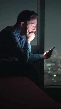 evening urban individual interacts with screen, man in city lights gazes at his illuminated device