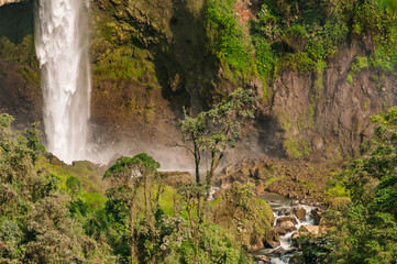 Waterfall amid the vegetation of cloud forests in the Colombian Andes, with the power of water falling between rocks and trees surrounded by the humidity of the environment.