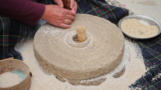 Traditional woman grinding wheat with ancient stone hand mill