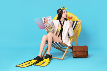Businesswoman with diving mask, magazine, cocktail and flippers in deck chair on light blue background © New Africa