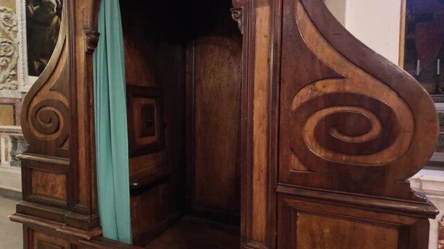 Old confessional in church interior, wooden structure with ornate decoration and sacred atmosphere