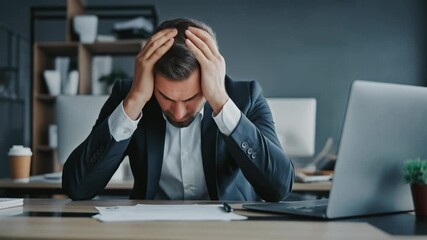 Stressed businessman in office showing signs of anxiety and burnout during work hours - Powered by Adobe