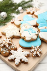 Tasty gingerbread cookies and Christmas decor on white wooden table, closeup