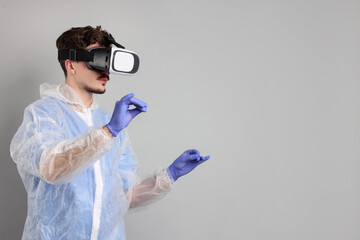 Modern technology. Doctor using virtual reality headset on grey background. Space for text