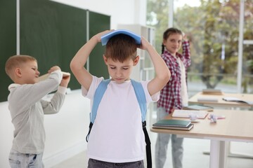 Boy getting bullied by his classmates in school, selective focus