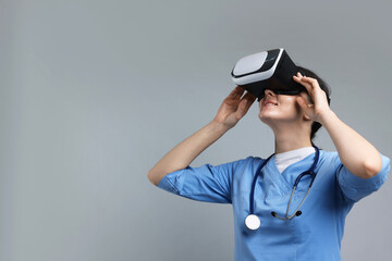 Modern technology. Doctor using virtual reality headset on grey background. Space for text