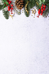 Festive Christmas border with fir tree branches and bright decorations on light blue marble...