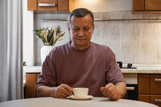 Adult man enjoying cup of coffee at kitchen table after homemade breakfast. Calm morning routine. Morning Home Cooking Making and Eating Breakfast