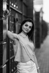 Black and white portrait of a confident woman with long dark hair, wearing a stylish sleeveless top, gazing thoughtfully at the camera, showcasing elegance and poise in a timeless manner