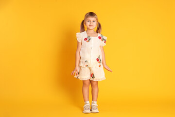 Cute little girl posing on yellow background