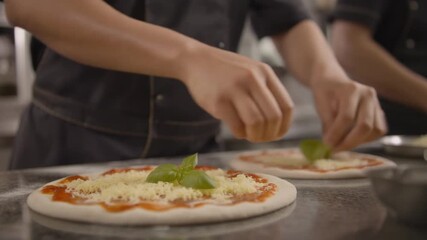 Professional chef adds basil and cheese toppings to pizza in a modern kitchen