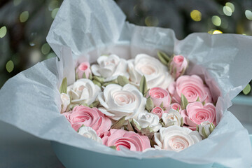 Beautiful arrangement of pink and white roses in a light blue gift box, surrounded by festive decorations, creating a charming holiday atmosphere with soft lighting