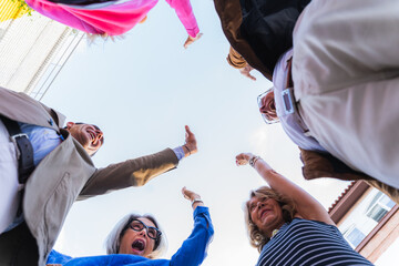 Mature friends high fiving in a huddle looking down