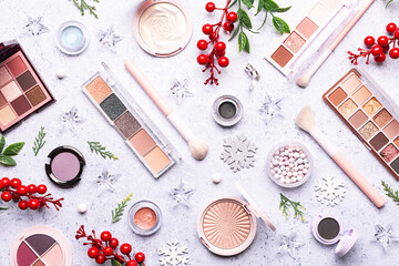 Bright Christmas and New Year composition with traditional festive decorations and decorative cosmetic products on blue stone background top view. Christmas cosmetic sale and promo banner. 