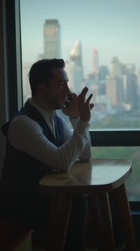 urban professional speaking during daytime, man engaged in business conversation at window seat