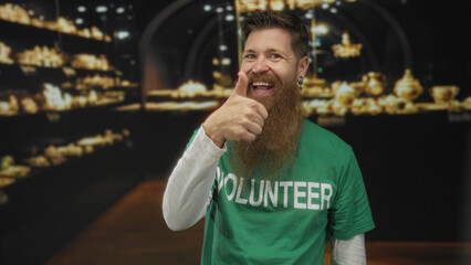 Man with beard pointing finger beside museum display in building gallery; volunteering community service excitement.