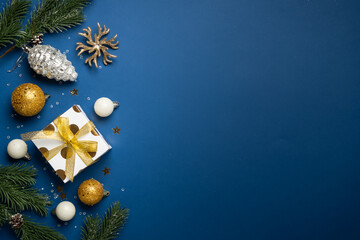 Naklejka premium White and golden Christmas decorations and gift box on navy background.