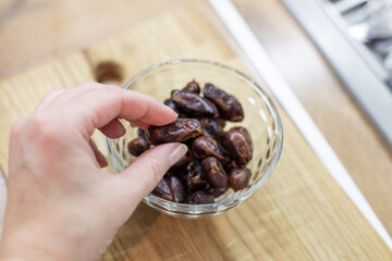 Hand picking dried date fruit from glass bowl