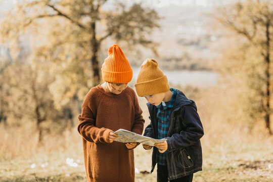 Children exploring with a map in autumn forest