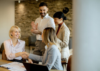 Team celebrates successful business deal in modern office setting during daytime