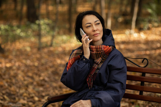 Woman in park enjoying autumn phone call - Powered by Adobe