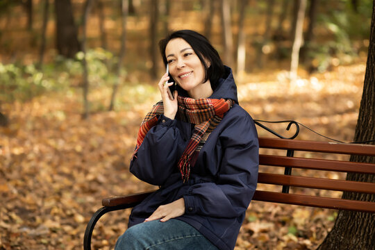 Woman chatting on phone in autumn park setting