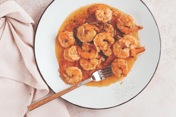 Savory shrimp dish served in a white plate with flavorful sauce and herbs