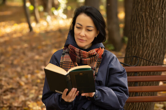 Woman reading a book on an autumn day in the park