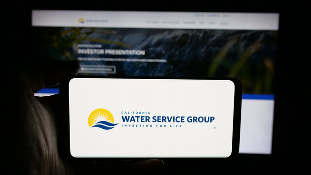 Stuttgart, Germany - 11-27-2025: Person holding cellphone with logo of US company California Water Service Group on screen in front of webpage. Focus on phone display.