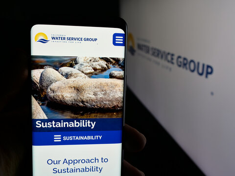Stuttgart, Germany - 11-27-2025: Person holding cellphone with webpage of US company California Water Service Group on screen in front of logo. Focus on center of phone display.