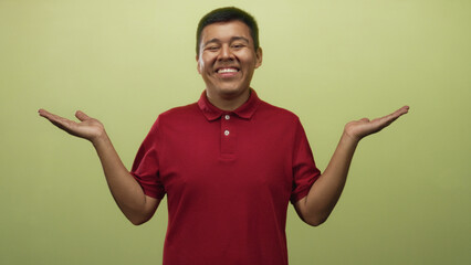 Young man showing open palms up gesture in a studio with a light green backdrop; choice balance curiosity.