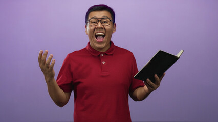 Man holding book and gesturing while reading in a purple studio; enthusiasm storytelling creative presentation.
