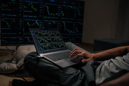 Skilled trader analyzing real-time stock market data and financial charts on laptop, closely monitoring multiple screens with cryptocurrency trends and investment indicators, close-up.