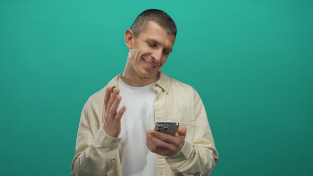 Caucasian man engaging with smartphone against isolated green background wall, highlighting expressions and gestures suggesting various emotions and interactions. - Powered by Adobe